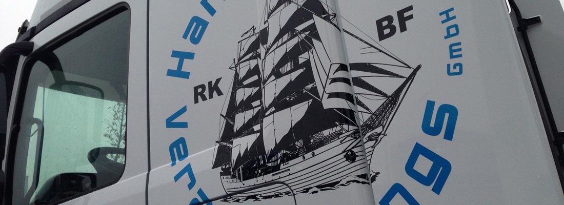 Fahrzeugbeschriftung LKW: großes Segelschiff-Motiv in Schwarz mit blauen Schriftzügen auf weißer Fahrerkabine – umgesetzt von Folien Fischer Hamburg